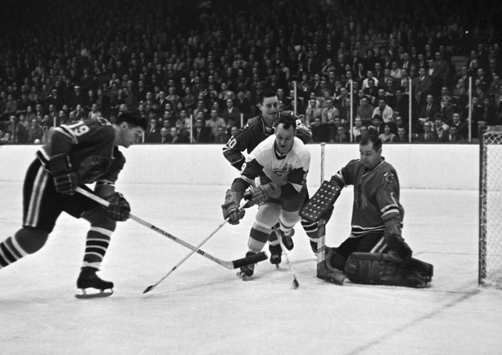 Detroit Red Wings' Gordie Howe (9) charges in but is ganged up on the three Chicago players, Al MacNeil (19), Doug Jarrett (20), and goalie Glenn Hall, who defend against the shot in first period of their NHL game in Chicago, March 16, 1966. THE CANADIAN PRESS/AP-Paul Cannon
