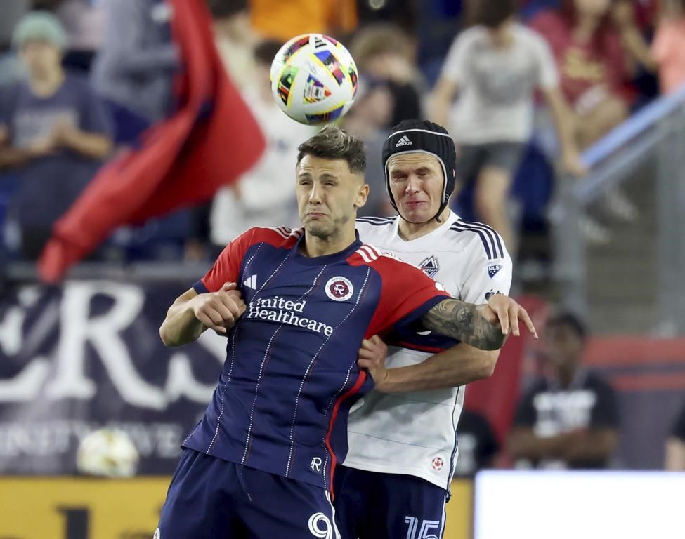 New England Revolution forward Giacomo Vrioni, left, and Vancouver Whitecaps defender Bjørn Inge Utvik, right, head the ball during the second half of an MLS soccer match in Foxborough, Mass., on June 15, 2024. THE CANADIAN PRESS/AP - Mark Stockwell
