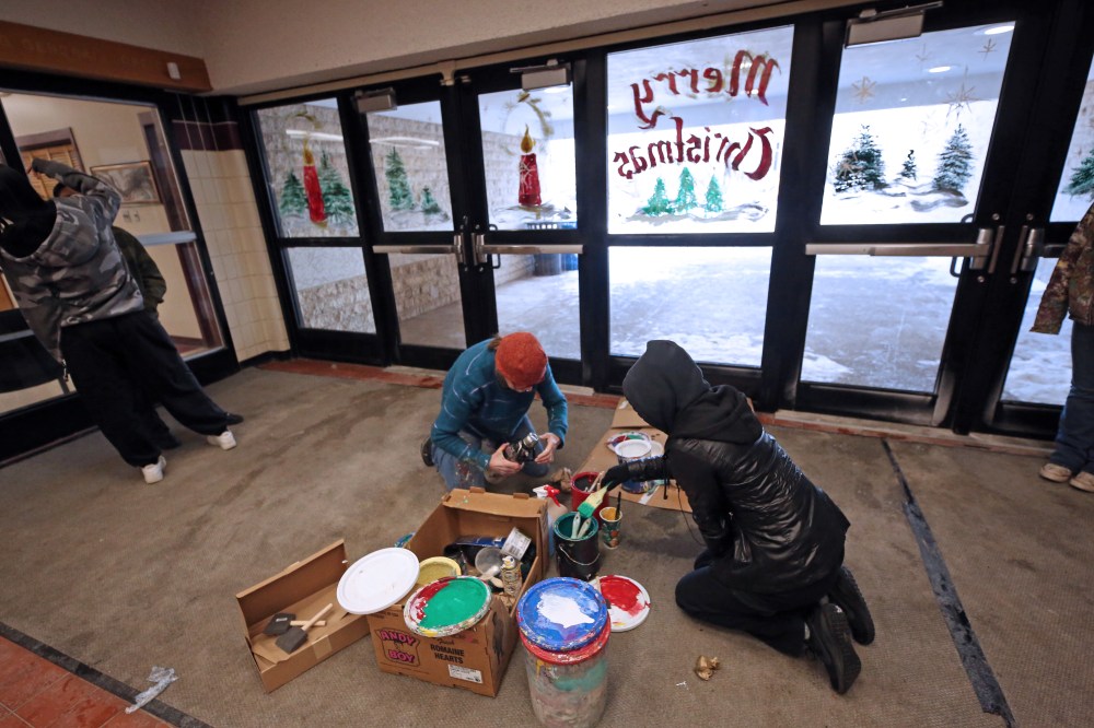 Painting instructor Anne Boychuk cleans up supplies with one of her students after painting the front doors of Crocus Plains Regional Secondary School on Friday morning. (Matt Goerzen/The Brandon Sun)