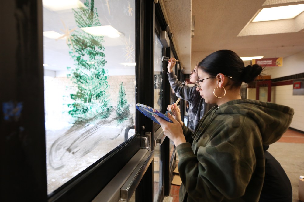 Grade 11 student Harmonee Moar-Sanderson dabs at her paint palette while painting stars on a front door window at Crocus Plains on Friday morning, part of an art project with Boychuk to paint a holiday theme on the high school’s front entrance. (Matt Goerzen/The Brandon Sun)