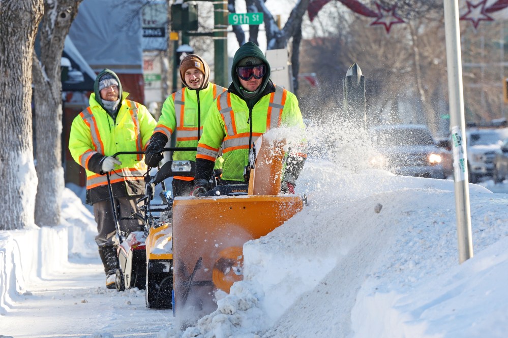 City of Brandon workers clear big snowdrifts from the sidewalk along Princess Avenue in downtown Brandon on Thursday after yet another big overnight snowfall. (Tim Smith/The Brandon Sun)