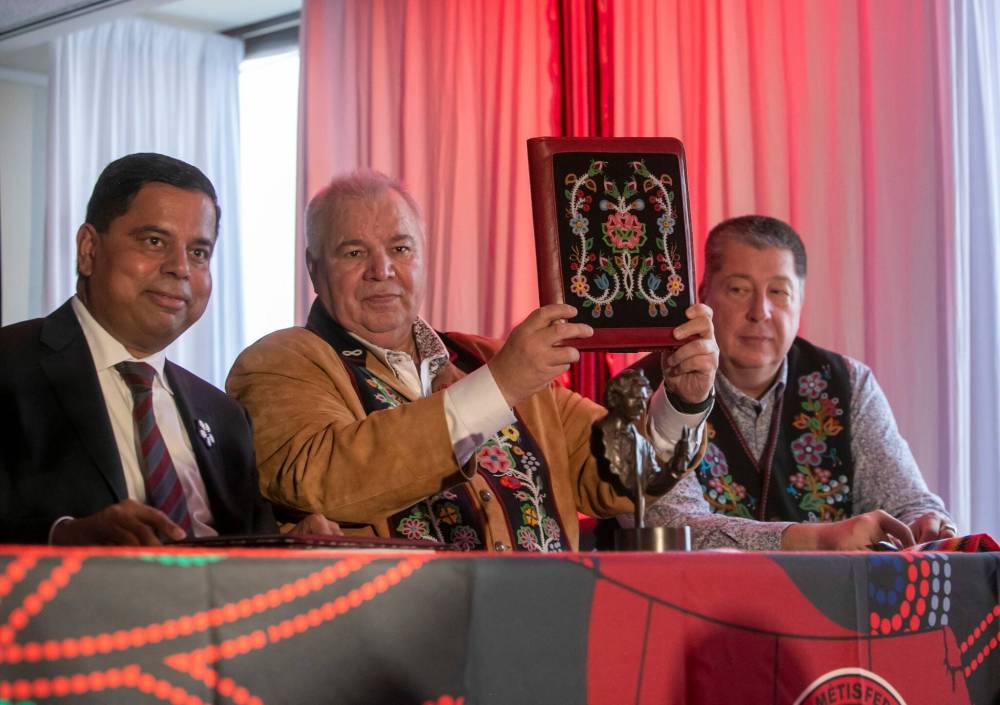 Manitoba Métis Federation President David Chartrand (middle) holds up a copy of the Red River Métis Self Government Treaty beween the Manitoba Métis Federation, National Government of the Red River Métis and his His Majesty King Charles III on bahalf of the Crown and the Government of Canada. The treaty signing ceremony took place in Winnipeg, Man. on Nov. 30, 2024. Pictured (L-R): Federal Minister of Crown-Indigenous Relations Gary Anandasangaree, Chartrand and lead negotiator for the Red River Métis Allan Benoit. Two Manitoba Dakota First Nations filed an injunction on Dec. 2 with the Manitoba Court of King’s Bench that seeks to have the treaty declared invalid. (Brook Jones/Winnipeg Free Press)