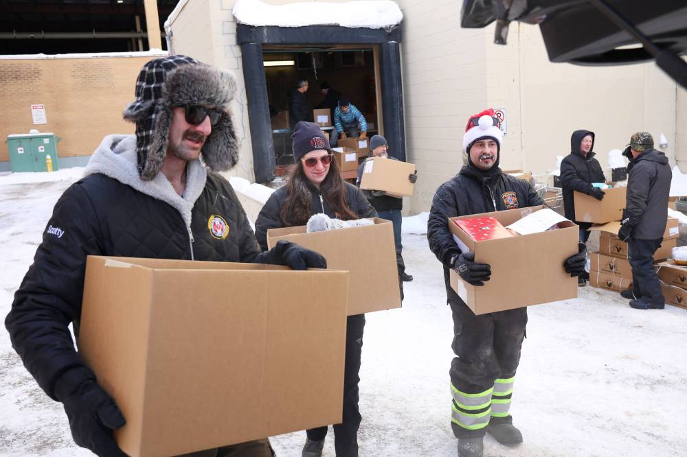 Scott Ryan, Kaitlyn May and Gage Wood with Brandon Fire and Emergency Services help load Christmas hampers into waiting vehicles outside Brandon-Westman Christmas Cheer on Wendesday.