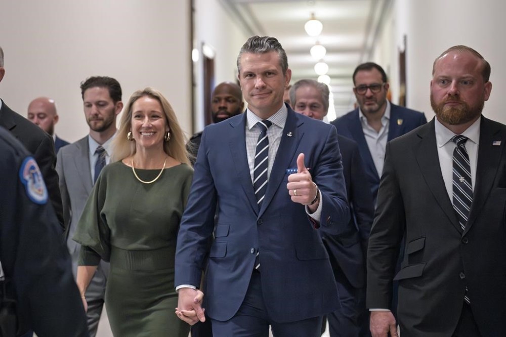 FILE - Pete Hegseth, President-elect Donald Trump's nominee to be Defense Secretary, gives a thumbs-up as he walks with his wife Jennifer Rauchet, left, to meet with Sen. Joni Ernst, R-Iowa, at the Capitol in Washington, Dec. 9, 2024. (AP Photo/J. Scott Applewhite, File)
