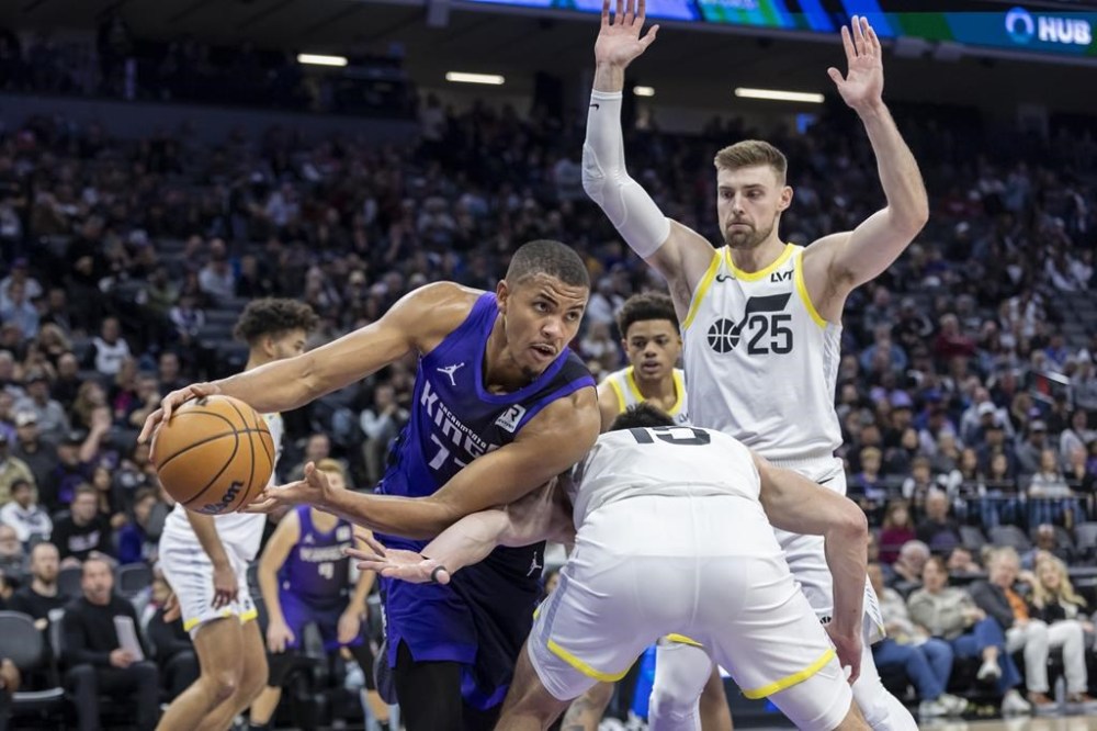 Sacramento Kings' Orlando Robinson, front left, looks to pass the ball around Utah Jazz forward Drew Eubanks, front right, during the first half of an NBA basketball game Sunday, Dec. 8, 2024, in Sacramento, Calif. THE CANADIAN PRESS/AP-Sara Nevis