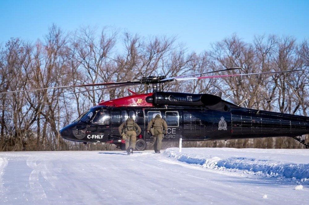 RCMP in Manitoba say residents near the U.S. border could start seeing and hearing Black Hawk helicopters on a regular basis as they increase their presence in the area. Officers in tactical gear approach an RCMP Black Hawk helicopter at a location along the U.S.-Canada border in an undated handout photo. THE CANADIAN PRESS/HO-Royal Canadian Mounted Police, *MANDATORY CREDIT*