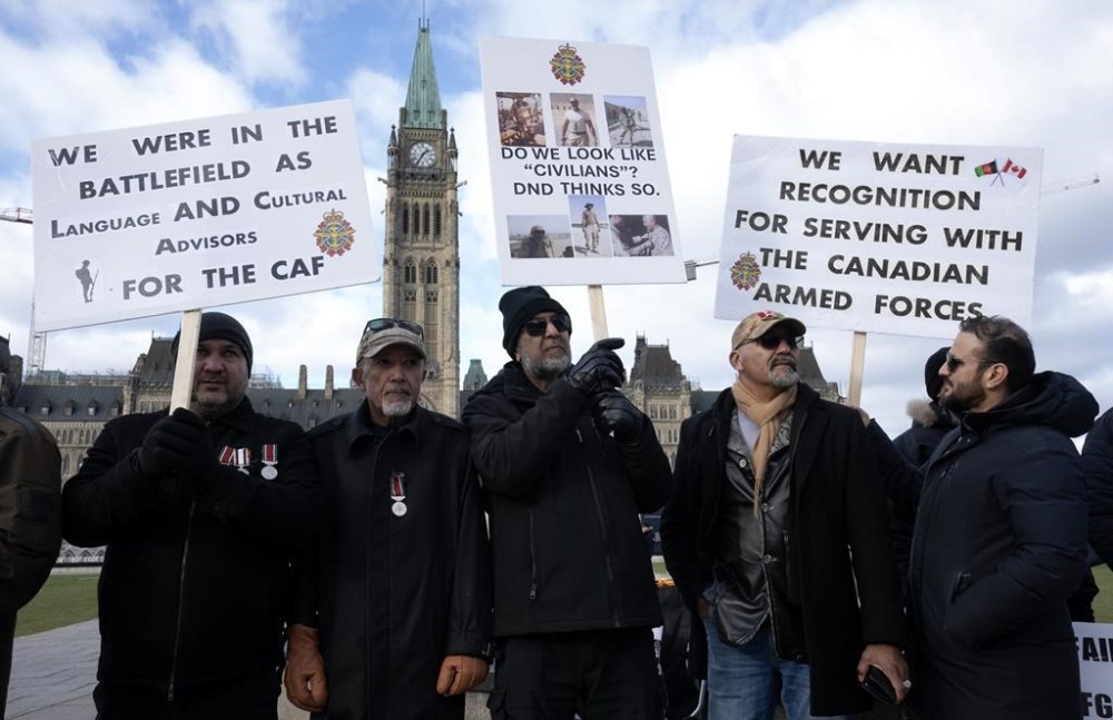 A military watchdog says Ottawa should financially compensate Afghan Canadians who served as interpreters for the Canadian Armed Forces in Afghanistan and later suffered mental distress. Language and cultural advisors for the Canadian Forces members protest on Parliament Hill, Tuesday, Nov.12, 2024 in Ottawa. THE CANADIAN PRESS/Adrian Wyld