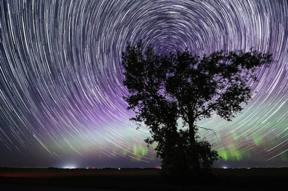 A lone tree, silhouetted by the shimmering northern lights on the horizon, stands in a field west of Forrest while a trail of stars circle the north star overhead. This image is a composite of 315 photos that were taken over the course of one hour. The photos were then “stacked” together using a computer program. The image allows us to see a visual representation of the rotation of the earth as the stars move in the night sky.