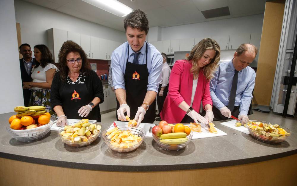 Educational assistant Kim Jemielity (from left), Prime Minister Justin Trudeau, Jenna Sudds — the federal minister of families, children and social development — and Winnipeg North Liberal MP Kevin Lamoureux prepare food for students at a food program at Elwick Community School in Winnipeg in May 2024. (File)