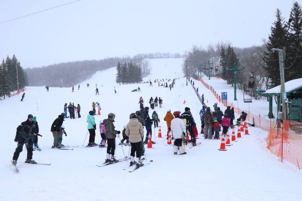 Ski and snowboard enthusiasts line up to board the chair lift at Holiday Mountain. (Matt Packwood/The Brandon Sun)