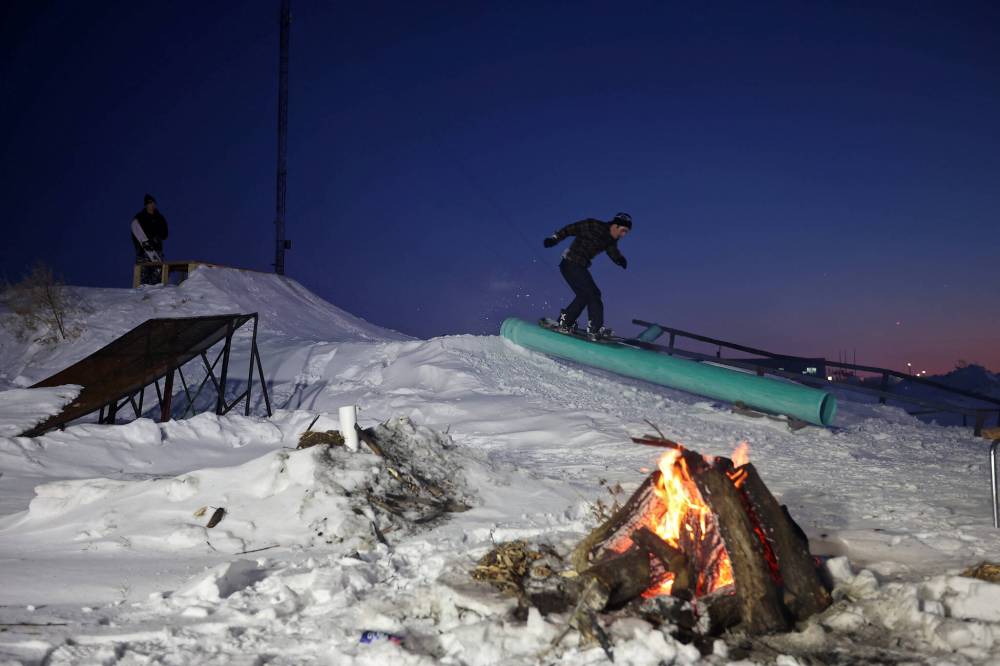 Nathan Rey grinds a tube while snowboarding in the backyard park at Campbell’s home on Wednesday evening.