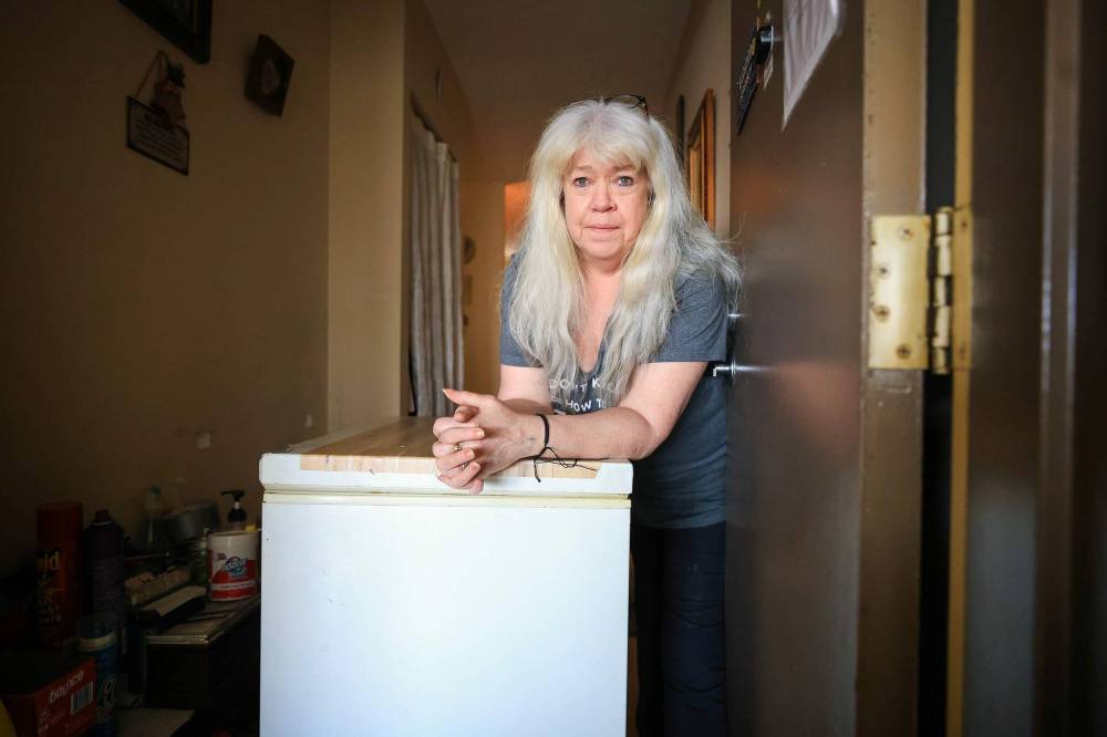 Moira Connolly stands next to her freezer that she has to push in front of her door each night to keep herself safe in her 55 Plus Manitoba Housing Complex in Winnipeg. (Ruth Bonneville/Winnipeg Free Press)