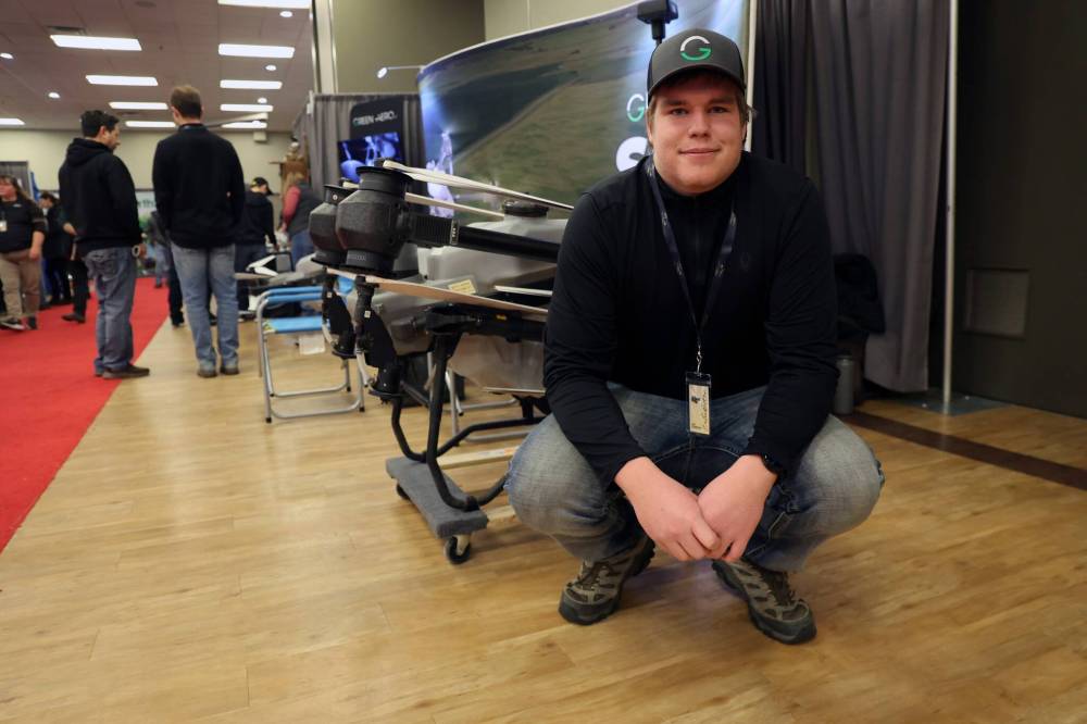 Kayden Wiersma crouches in front of an agricultural drone, the DJI AGRAS T50, at the Keystone Centre during Ag Days. Wiersma is a drone technician and one of many in the ag industry that have leaned into drones as an emerging technology to spray crops and spread seeds. (Connor McDowell/The Brandon Sun)