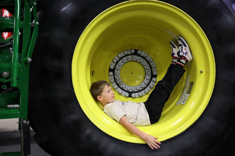 Atlas Friesen, 6, of Altona, rests in the wheel well of a John Deere combine during the final day of Manitoba Ag Days at the Keystone Centre on Thursday.
