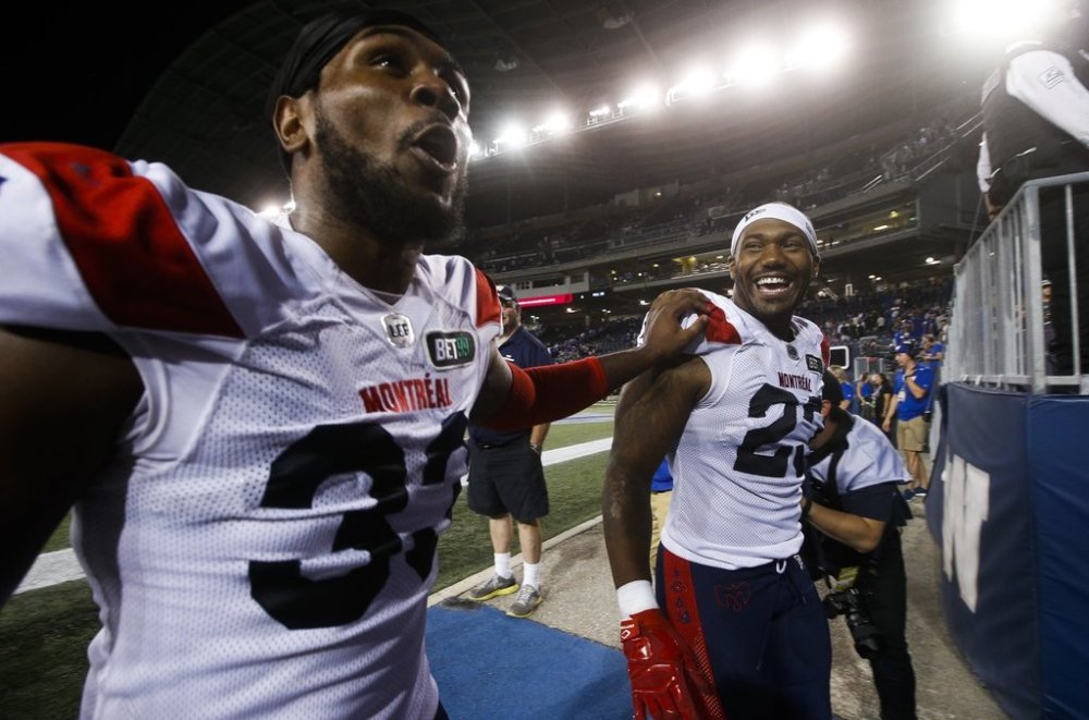 Montreal Alouettes' Keishawn Bierria (33) and Avery Ellis (23) celebrate a CFL overtime win over the Winnipeg Blue Bombers in Winnipeg, Thursday, August 11, 2022. They're a Super Bowl party staple yet for Avery Ellis, not all chicken wings are created equal. THE CANADIAN PRESS/John Woods