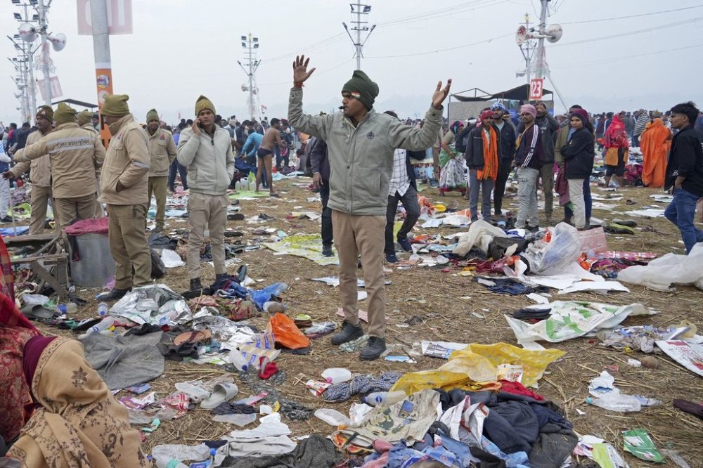 A policeman gestures as the belongings of Hindu devotees lie scattered after a stampede when Hindu devotees rushed to take a holy bath in the Sangam, the confluence of the Ganges, the Yamuna and the mythical Saraswati rivers, on
