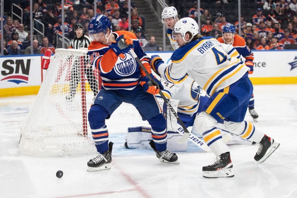 Buffalo Sabres' Bowen Byram (4) and Edmonton Oilers' Ryan Nugent-Hopkins (93) battle for the rebound during second period NHL action in Edmonton on Saturday, January 25, 2025. THE CANADIAN PRESS/Jason Franson