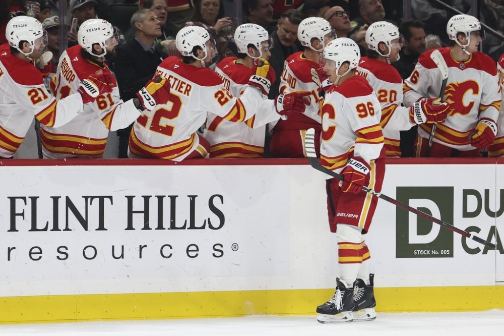 Calgary Flames left wing Andrei Kuzmenko (96) celebrates at the bench after scoring a goal during the first period of an NHL hockey game against the Minnesota Wild, Saturday, Jan. 25, 2025, in St. Paul, Minn. (AP Photo/Ellen Schmidt)