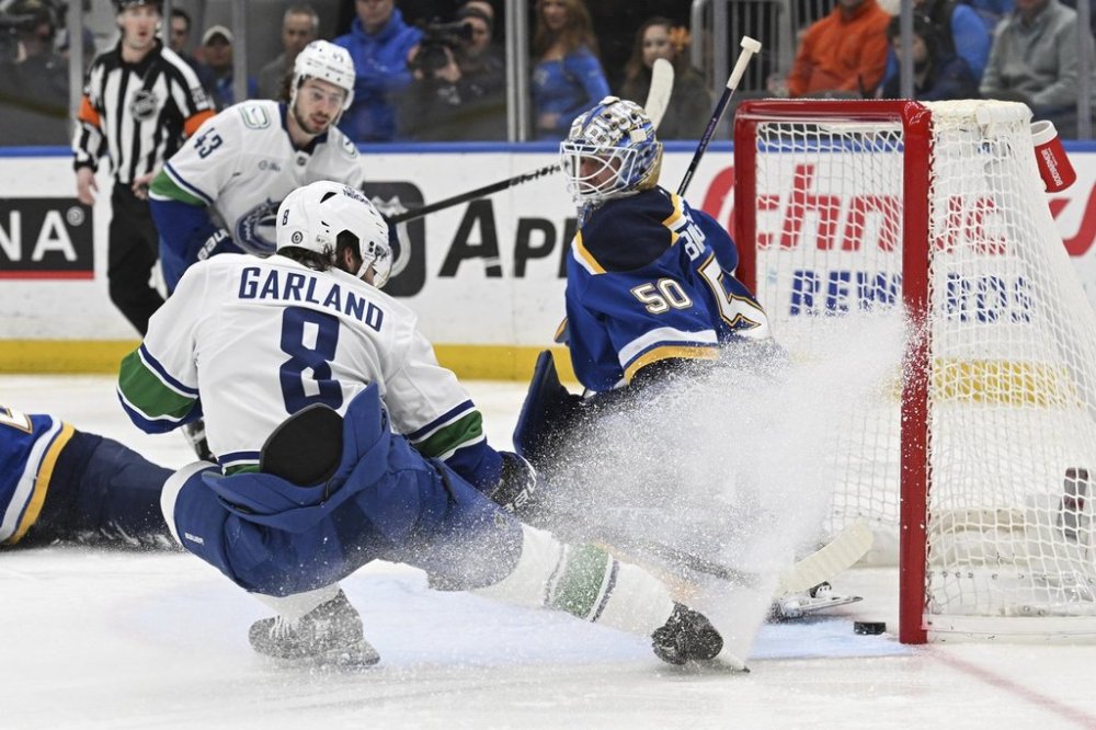 Vancouver Canucks' Conor Garland (8) scores past St. Louis Blues goaltender Jordan Binnington (50) during the first period of an NHL hockey game Monday, Jan. 27, 2025, in St. Louis. (AP Photo/Joe Puetz)