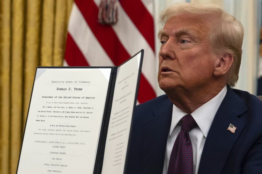 President Donald Trump holds up a signed executive order relating to clemency for anti-abortion protesters as he signs executive orders in the Oval Office of the White House, Thursday, Jan. 23, 2025, in Washington. (AP Photo/Ben Curtis)