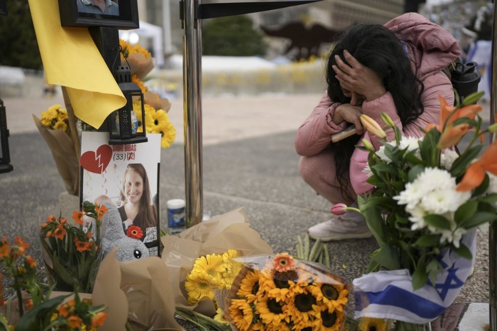 A woman mourns in a memorial for deceased hostages Shiri Bibas, her two children, Ariel and Kfir and Oded Lifshitz at 'Hostages Square', where Israelis are gathering while waiting for the release of six hostages in Gaza, in Tel Aviv, Israel, Saturday Feb. 22, 2025. (AP Photo/Oded Balilty)