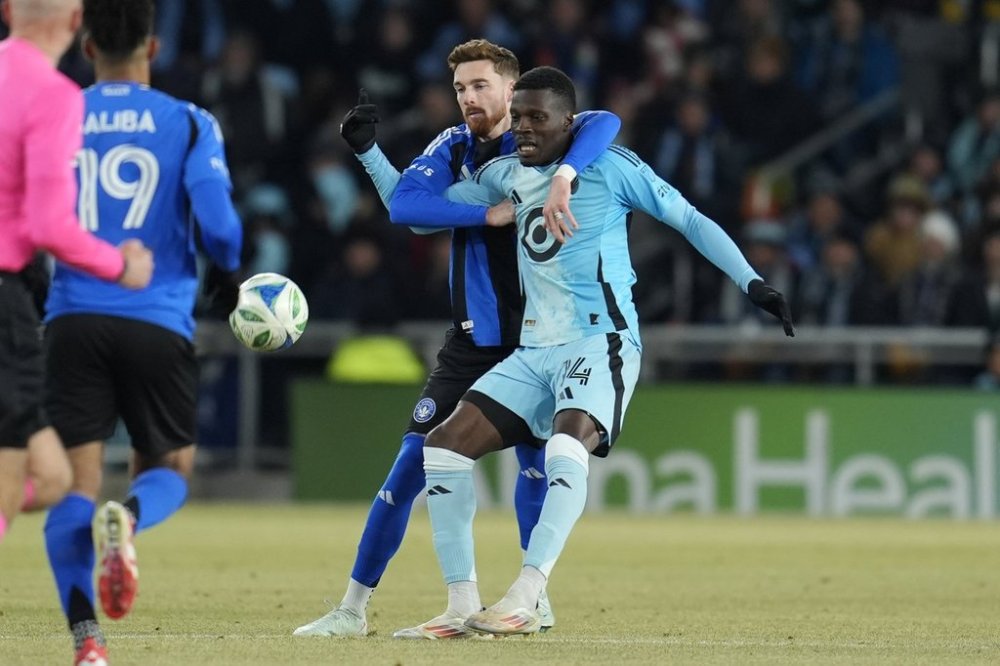 Minnesota United forward Tani Oluwaseyi (14) and CF Montreal defender Joel Waterman, centre left, battle for possession during the first half of an MLS soccer match in St. Paul, Minn., Saturday, March 1, 2025. (AP Photo/Abbie Parr)