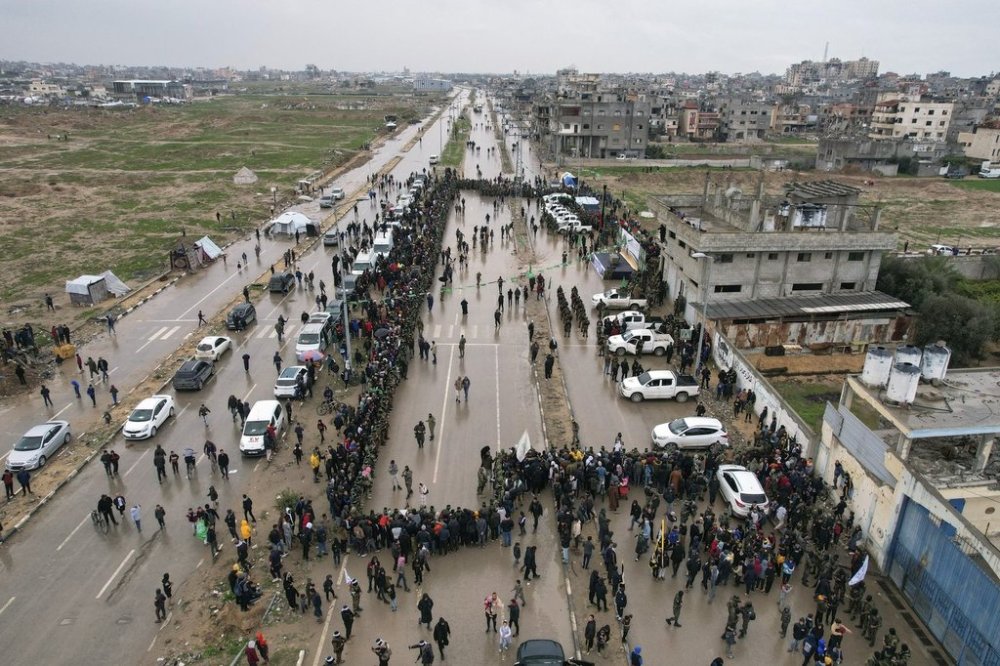 Palestinians gather as Hamas fighters deploy ahead of the planned release of Israeli hostages set to be handed over to the Red Cross in Nuseirat, central Gaza Strip, Saturday, Feb. 22, 2025. (AP Photo/Mohammad Abu Samra)