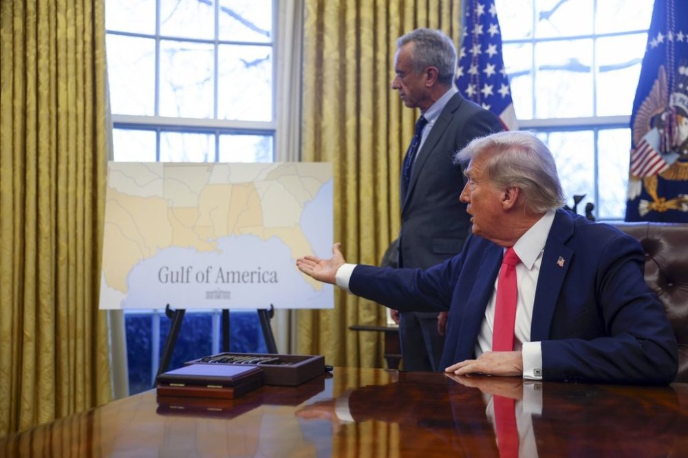 President Donald Trump gestures to a poster reading