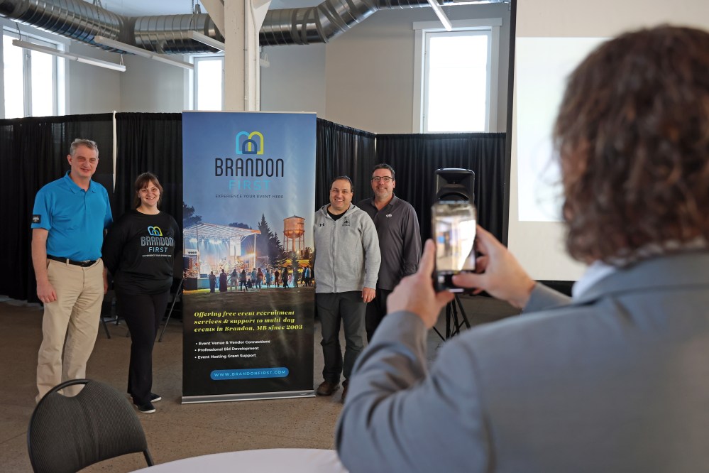 Brandon Mayor Jeff Fawcett takes photos of Coun. Bruce Luebke (Ward 6), who’s also the chair of the Keystone Centre board, Brandon First executive director Jenn Watson, Coun. Jason Splett (Ward 8) and Brandon First Board chair Chris Heide with the new Brandon First branding after the unveiling at the Dome Building on Thursday. (Tim Smith/The Brandon Sun)