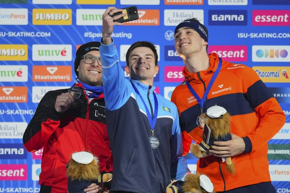 500-metre race winner Yevgeniy Koshkin of Kazakhstan takes selfie on the pdoium with second-place Laurent Dubreuil of Canada, left, and third-place Jenning De Boo of the Netherlands during World Cup Speedskating at the Thialf ice arena in Heerenveen, northern Netherlands, Sunday, March 2, 2025. (AP Photo/Peter Dejong)