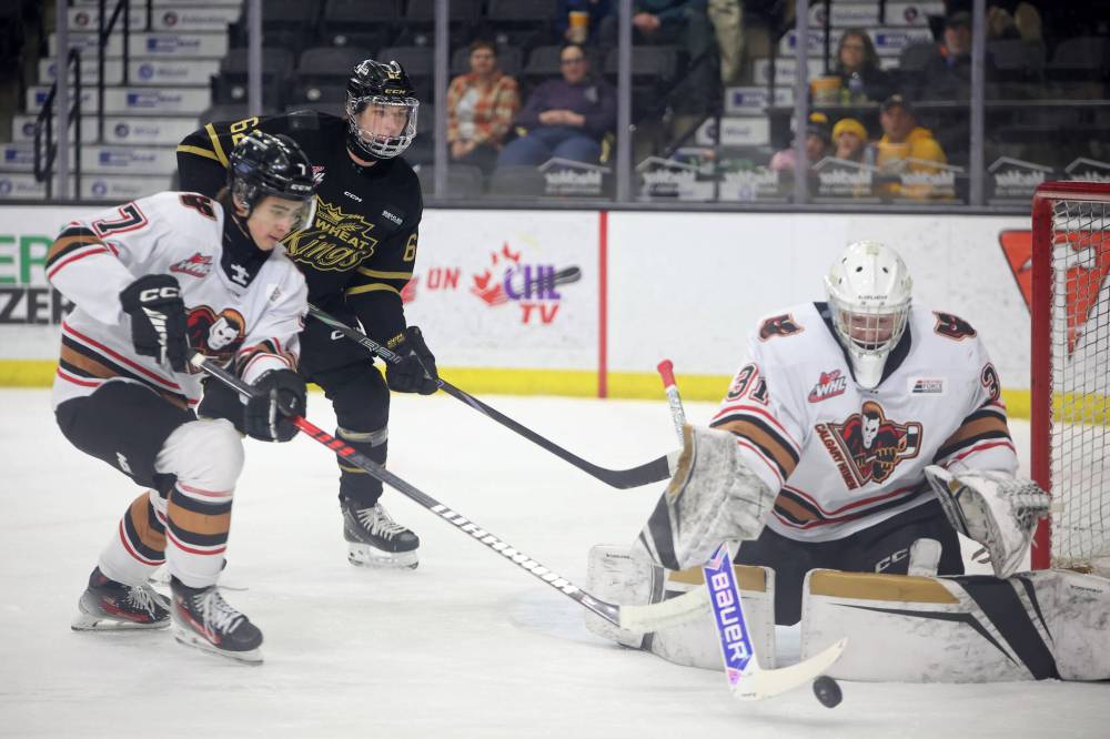 Nicholas Johnson (62) watches as goalie Daniel Hauser of the Hitmen deflects a shot on net Friday evening. (Tim Smith/The Brandon Sun)