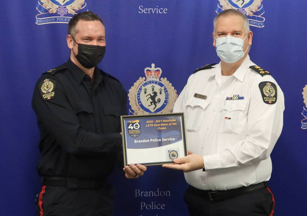 Const. Myran Hamm (left) accepts the Manitoba Law Enforcement Torch Run Guardians of the Flame award from then-Brandon Police Service chief Wayne Balcaen in late 2021. Hamm has been charged in connection with an incident from September 2023. (The Brandon Sun files)