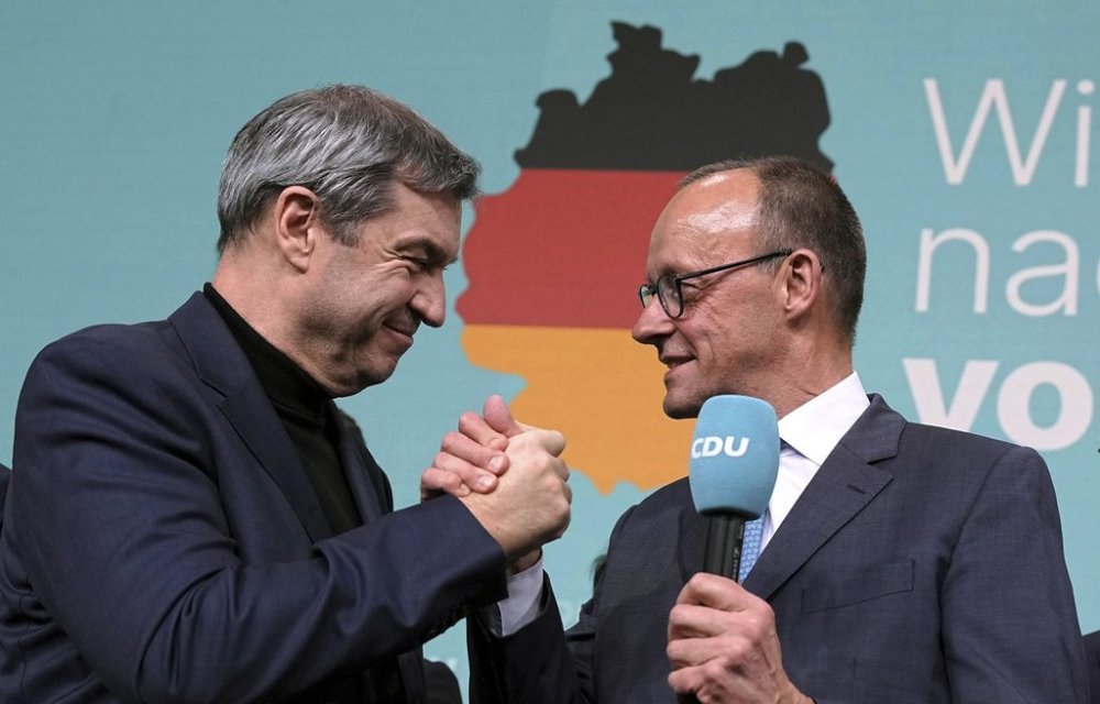 Friedrich Merz, right, leader of the Christian Democratic Union (CDU), and Markus Soeder, leader of the Christian Social Union (CSU), shake hands at the CDU party headquarters in Berlin, Germany, Sunday, Feb. 23, 2025. (Michael Kappeler/dpa via AP)