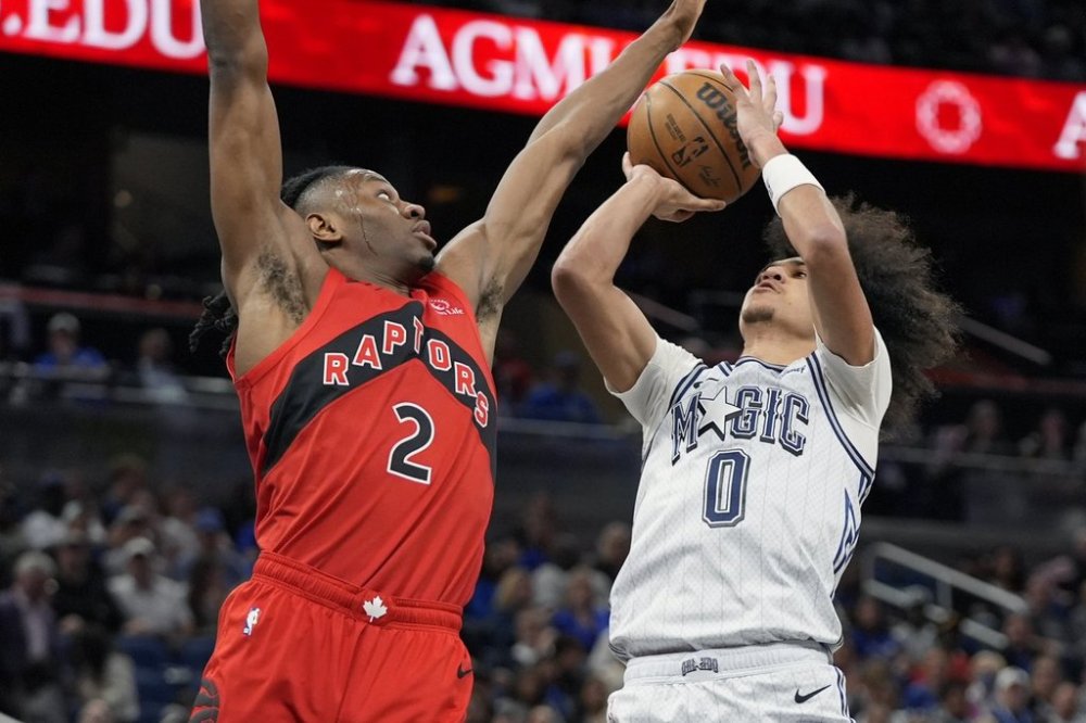 Orlando Magic guard Anthony Black (0) shoots against Toronto Raptors forward Jonathan Mogbo during the first half of an NBA basketball game Sunday, March 2, 2025, in Orlando, Fla. (AP Photo/John Raoux)