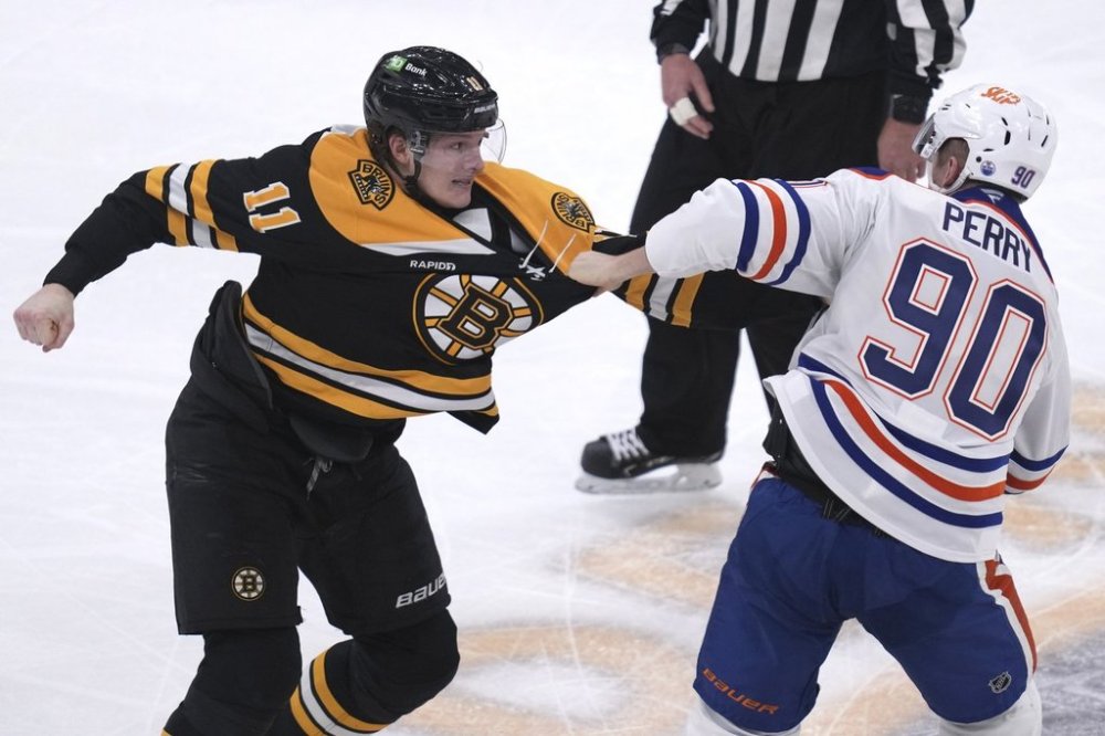 Boston Bruins centre Trent Frederic (11) fights Edmonton Oilers winger Corey Perry (90) during an NHL hockey game, Tuesday, Jan. 7, 2025, in Boston. (AP Photo/Charles Krupa)