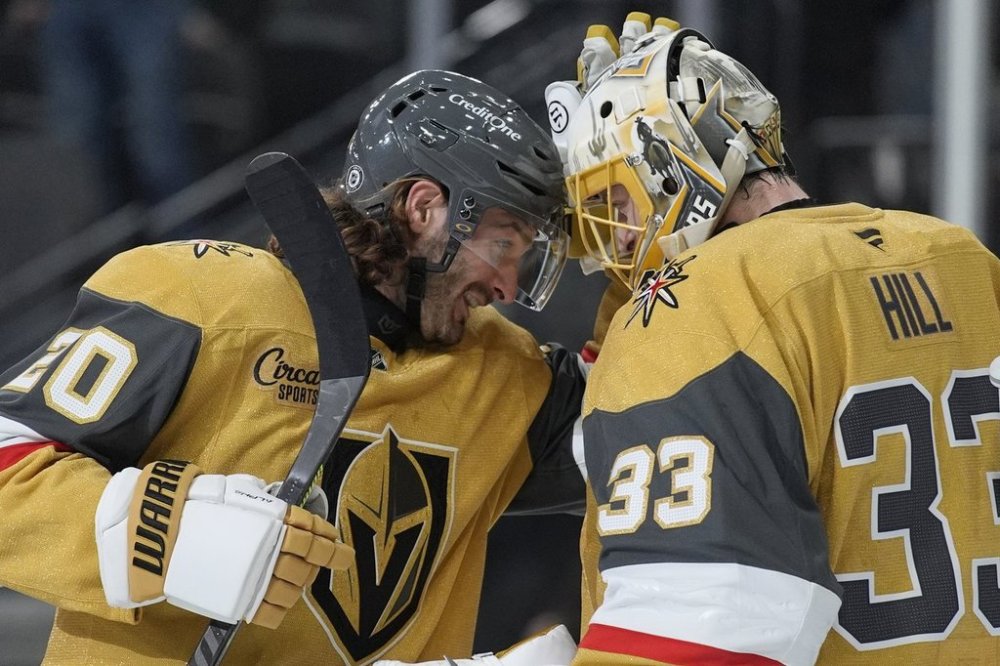 Vegas Golden Knights left wing Brandon Saad (20) and goaltender Adin Hill (33) celebrate after their team defeated the Vancouver Canucks in an NHL hockey game Saturday, Feb. 22, 2025, in Las Vegas. (AP Photo/John Locher)