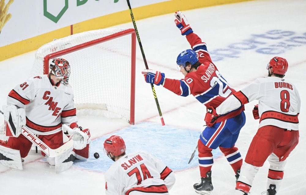 Montreal Canadiens' Juraj Slafkovsky (20) reacts to a goal by teammate Lane Hutson (not shown) on Carolina Hurricanes goaltender Frederik Andersen (31) as Hurricanes' Jaccob Slavin (74) and Brent Burns (8) defend during third period NHL hockey action in Montreal, Tuesday, February 25, 2025. THE CANADIAN PRESS/Graham Hughes
