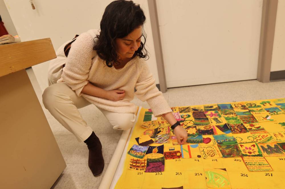 Brandon resident Eftihia Mihelakis places her painted tiles in the mosaic.