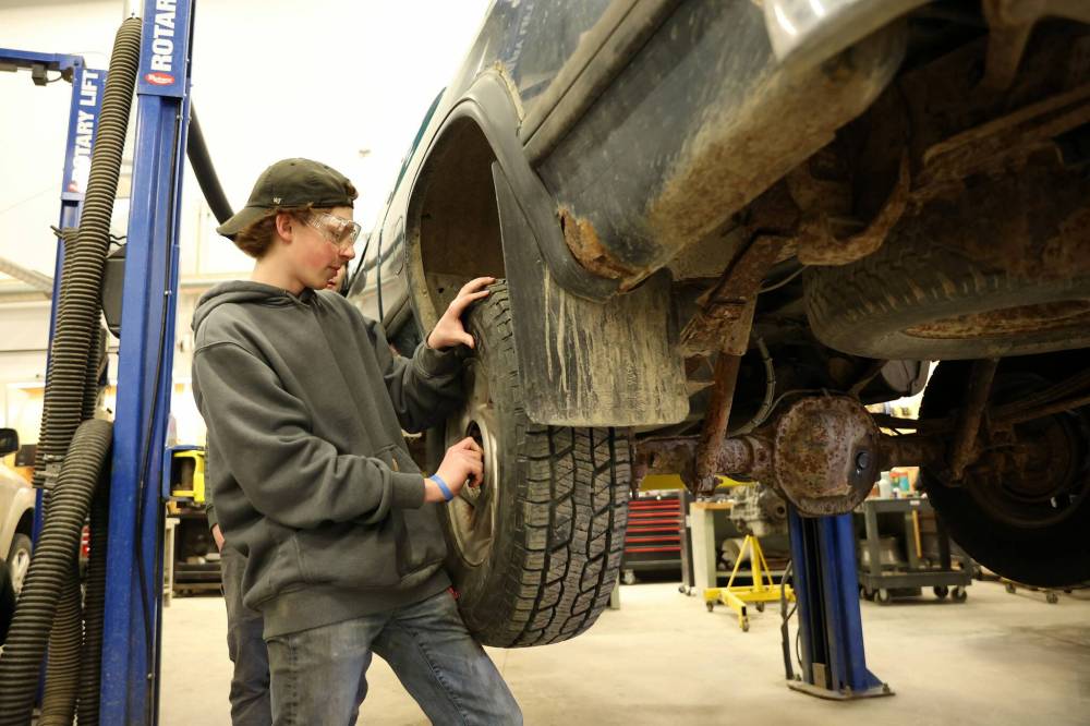 Cooper Kirkpatrick, a Grade 12 student from Crocus Plains Regional Secondary School, changes a tire during a tour of the automotive technician program at Assiniboine College’s North Hill campus as part of the third annual Trades Summit on Thursday. Approximately 380 high school students took part in the summit. (Tim Smith/The Brandon Sun)