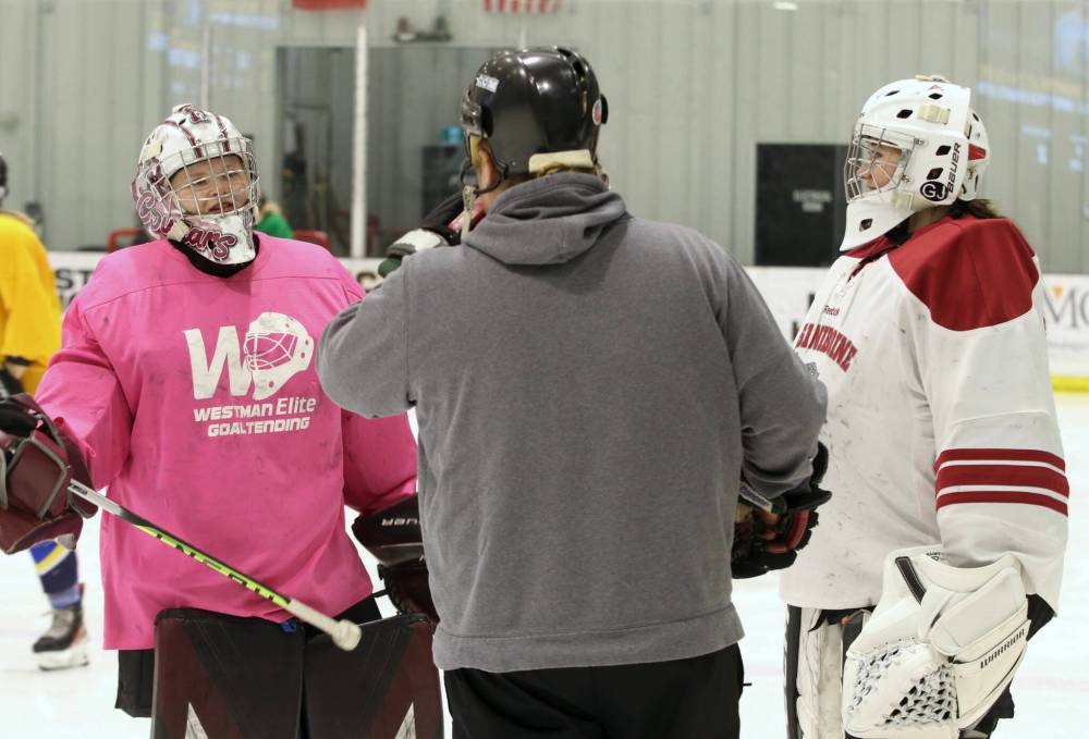 Cougars goaltenders Payton Murray (left) and Rachel Halldorson (right) speak with assistant coach Jeff Moore at one of the team’s final on-ice training sessions before ACHA nationals. (Matt Packwood/The Brandon Sun)