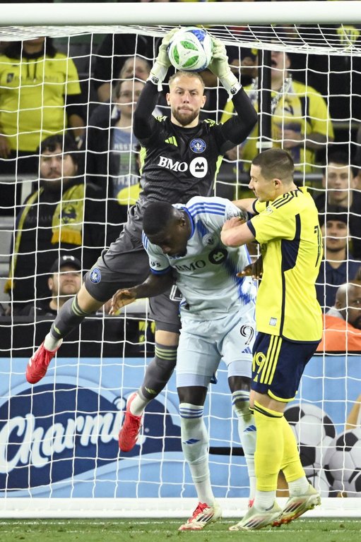 CF Montréal goalkeeper Jonathan Sirois, top, makes a save in front of CF Montréal forward Prince Osei Owusu (9) and Nashville SC midfielder Alex Muyl (19) during the first half of an MLS soccer match Saturday, March 22, 2025, in Nashville, Tenn. (AP Photo/John Amis)