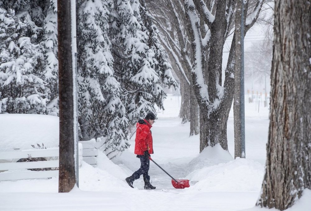A person shovels after heavy snowfall in Edmonton on March 28, 2025. A winter storm has slammed through parts of Canada with a wallop of heavy snow and freezing rain, turning roads into a smash-up derby. THE CANADIAN PRESS/Jason Franson