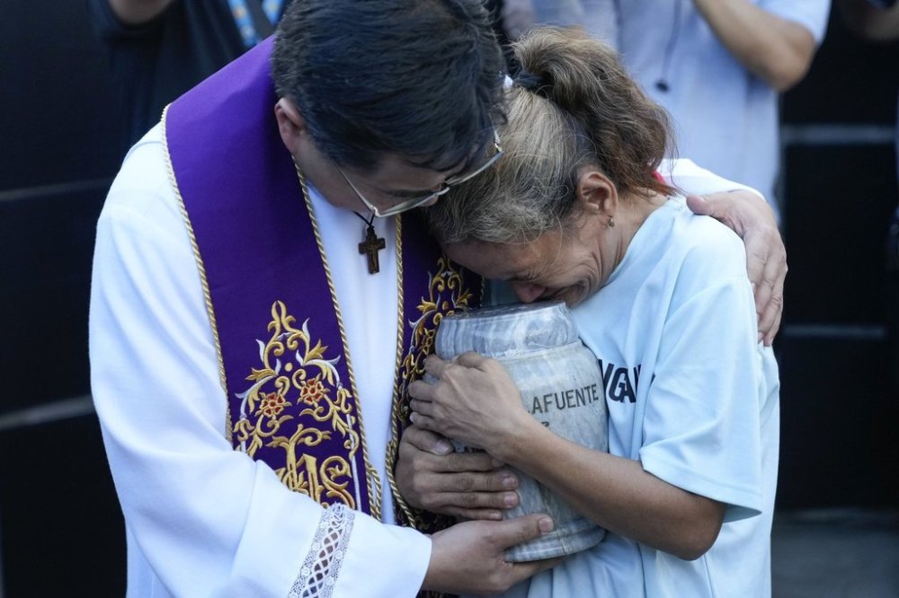 Filipino Catholic priest Flavie Villanueva, left, consoles Melinda Lafuente, as she holds the urn containing the remains of her son Angelo, during an interment ceremony for victims of extrajudicial killings, at the