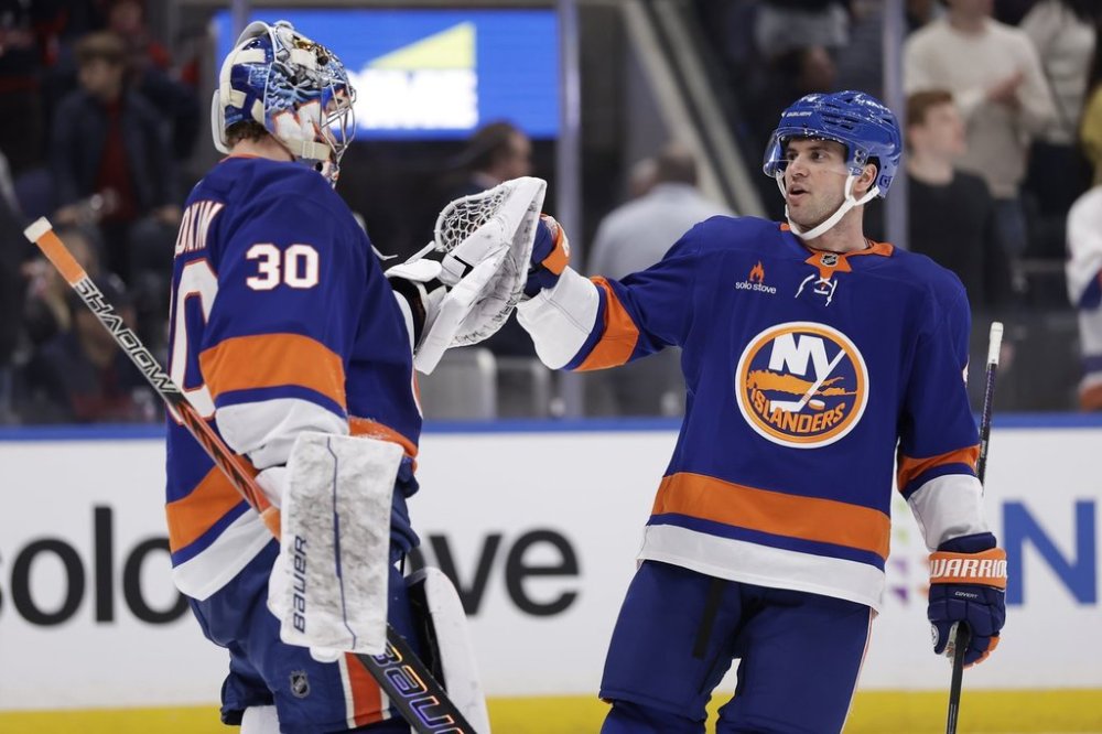 New York Islanders goaltender Ilya Sorokin (30) and New York Islanders defenceman Tony DeAngelo (4) bump fists after an NHL hockey game against Washington Capitals in Elmont, N.Y., Sunday, April 6, 2025. (AP Photo/Adam Hunger)