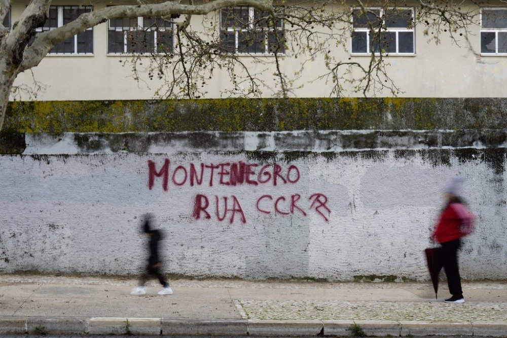 People walk past a graffiti saying