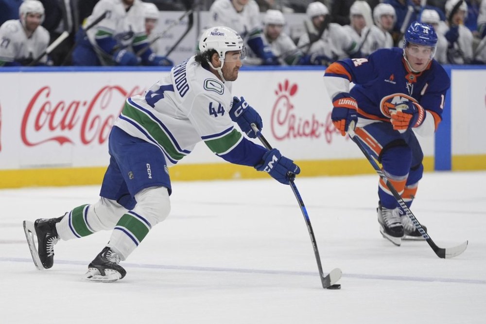 Vancouver Canucks' Kiefer Sherwood (44) looks to pass away from New York Islanders' Bo Horvat (14) during the second period of an NHL hockey game Wednesday, March 26, 2025, in Elmont, N.Y. (AP Photo/Frank Franklin II)