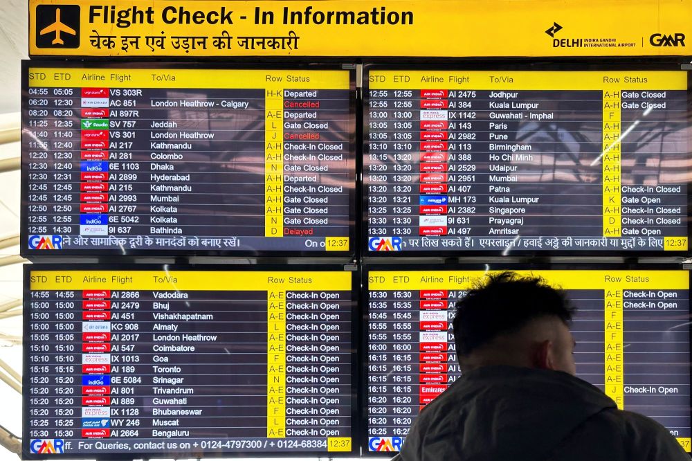 A passenger stands in front of a flight information screen showing cancelled flights destined for the Heathrow Airport in London, at the Indira Gandhi International Airport, in New Delhi, India, Friday, March 21, 2025. (AP Photo/Shonal Ganguly)