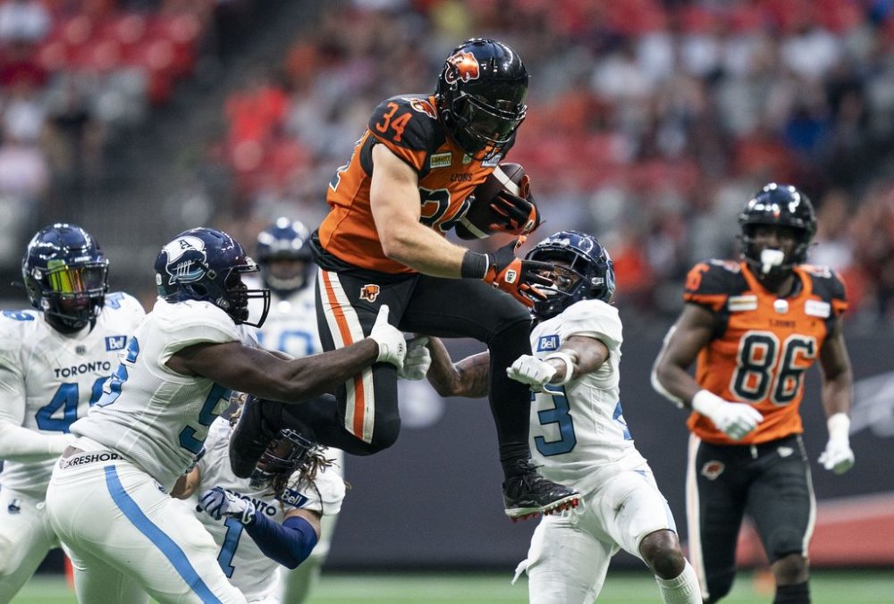BC Lions' David Mackie tries to jump over the tackle of Toronto Argonauts' Shaquille Richardson and Sam Acheampong (left) and Robert Priester (second from right) during second half of CFL football action in Vancouver, B.C., Saturday, June 25, 2022. THE CANADIAN PRESS/Rich Lam