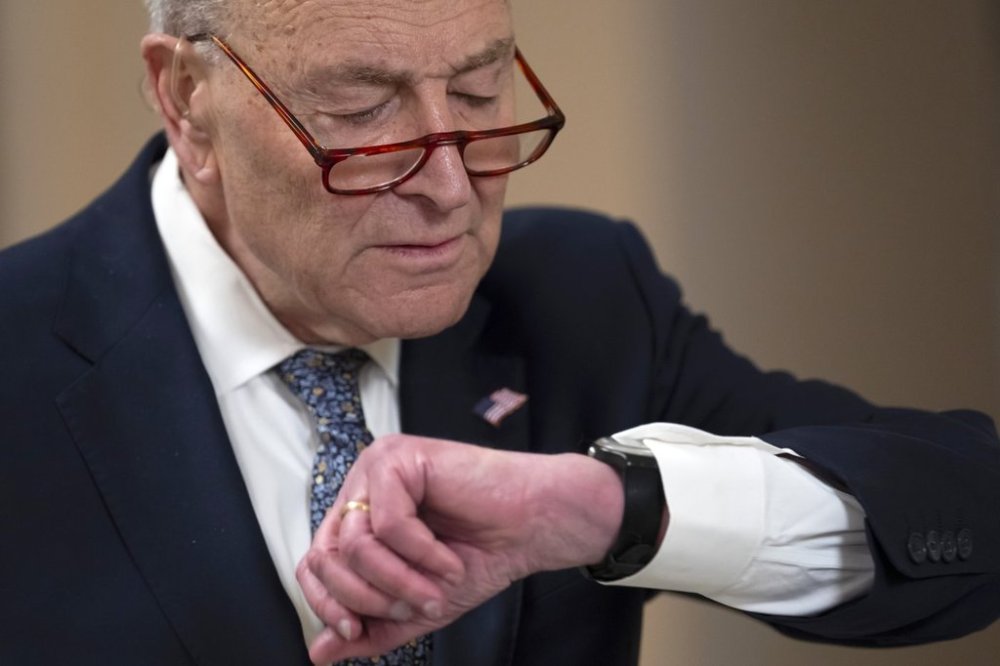 Senate Minority Leader Chuck Schumer, D-N.Y., looks at his watch before a television interview as the Senate works to avert a partial government shutdown ahead of the midnight deadline, at the Capitol in Washington, Friday, March 14, 2025. (AP Photo/Ben Curtis)