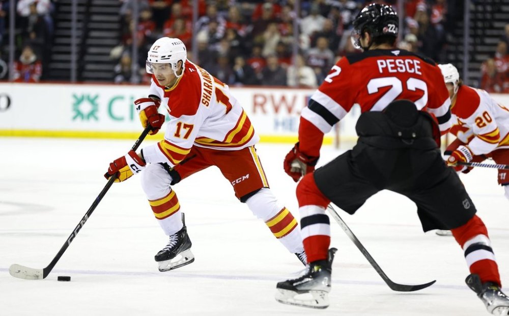 Calgary Flames center Yegor Sharangovich (17) controls the puck in front of New Jersey Devils defenseman Brett Pesce (22) during the first period of an NHL hockey game, Thursday, March 20, 2025, in Newark, N.J. (AP Photo/Noah K. Murray)